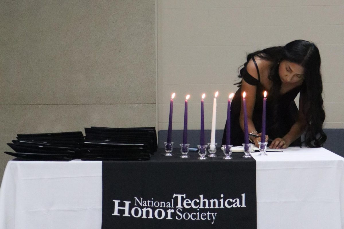 Senior Aileen Guerrero signs the NTHS Chapter Register during the induction ceremony.